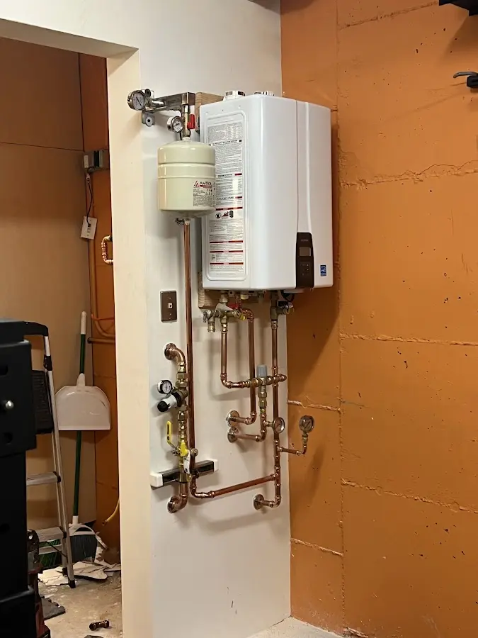 Plumbing technician inspecting water heater connections in Brownville